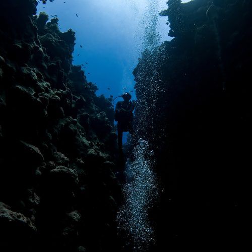 buceador entre burbujas saliendo de entre dos rocas