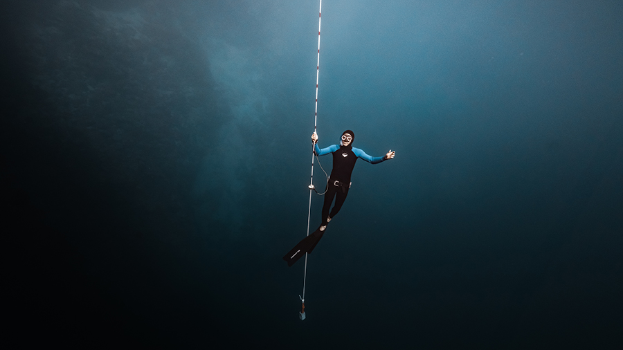 apneísta en el cabo con los brazos abiertos, levitando cabeza arriba, en el Blue Hole de Dahab